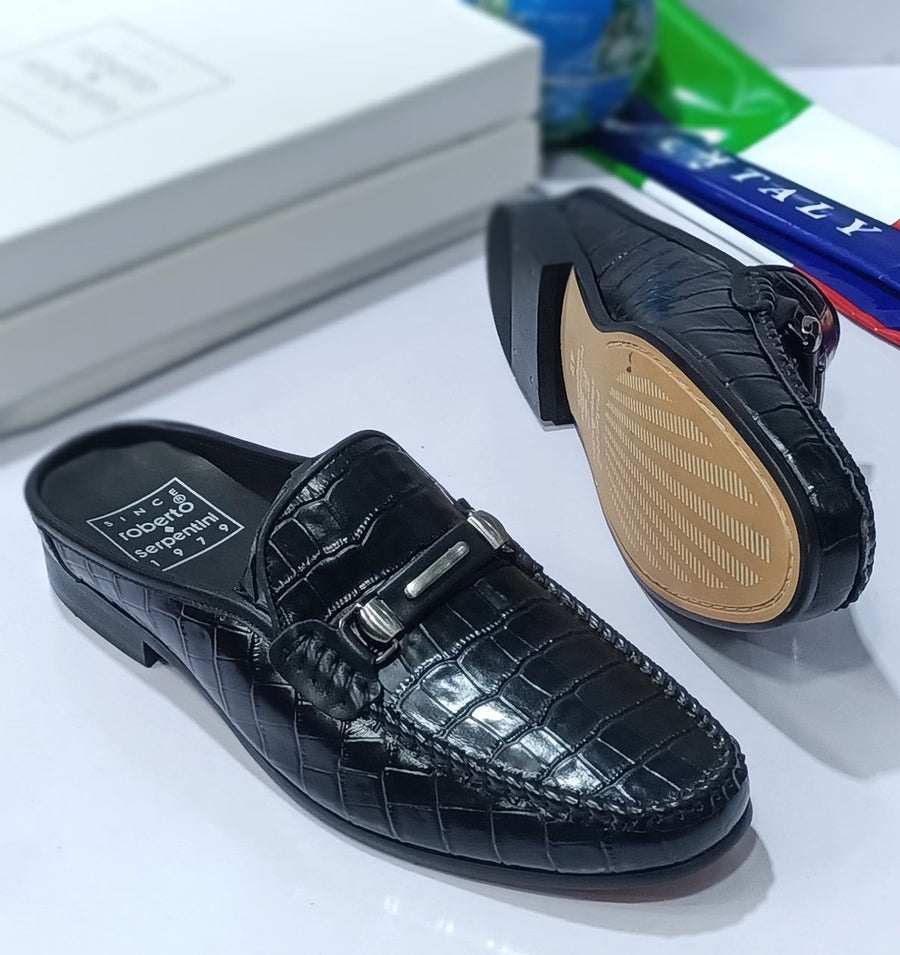 Black slip-on shoe with textured sole on a white background